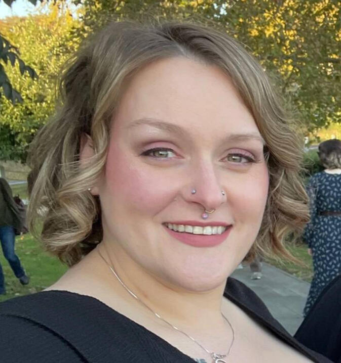 Photo of Jordan, a fair skinned woman with light brown hair in a dark colored dress.